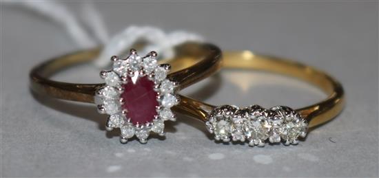 A ruby and diamond 9ct gold cluster ring and an 18ct gold and three-stone diamond ring.